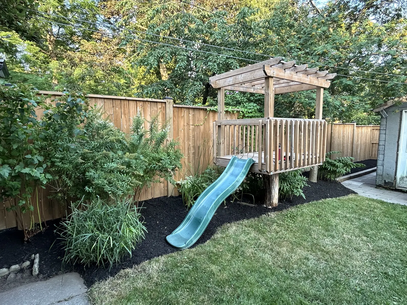 Backyard play structure framed by established planting